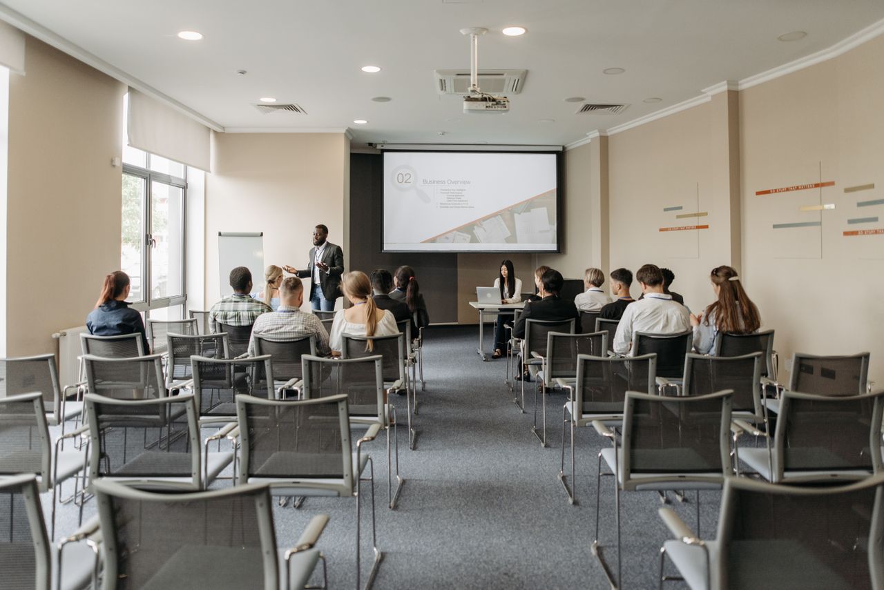 Mastering the First Impression: Your intriguing post title goes here A group attending a business presentation in a modern conference room with projector.